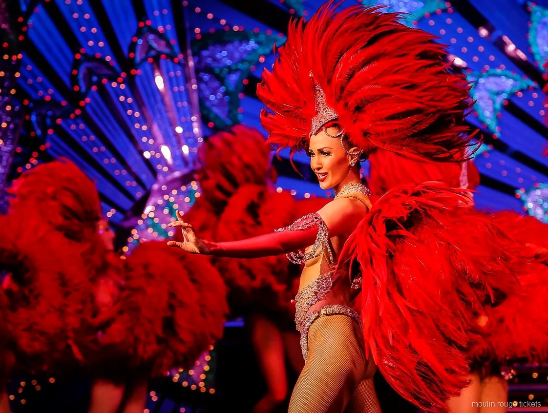 Dançarina com um grande leque de penas vermelhas diante de um cenário azul iluminado, bilhetes Moulin Rouge