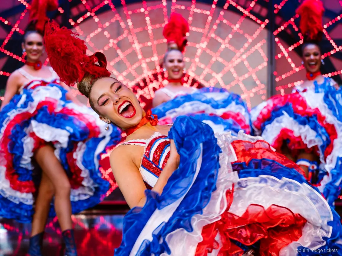 Bailarina de cancán riendo con falda de volantes roja, blanca y azul, cena espectáculo Moulin Rouge