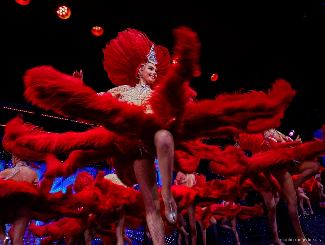 Bailarinas agitando grandes abanicos de plumas rojas en una patada alta, cena espectáculo Moulin Rouge