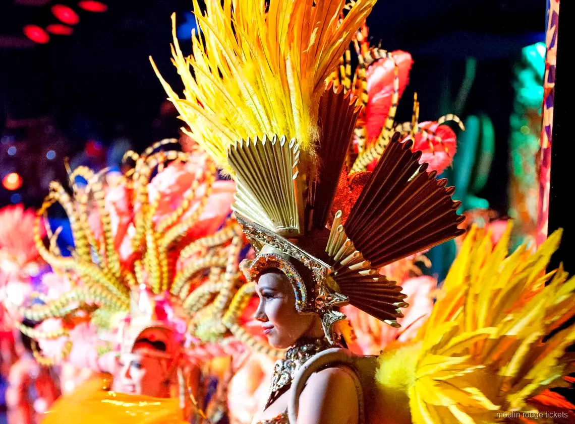 Bilhetes Moulin Rouge: dançarina com cocar de penas douradas e coroa em leque no palco