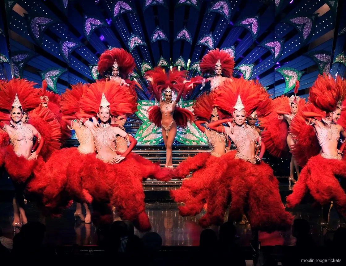 Danseuses en costumes de plumes rouges et coiffes scintillantes sur scène, la revue vue avec des billets Moulin Rouge