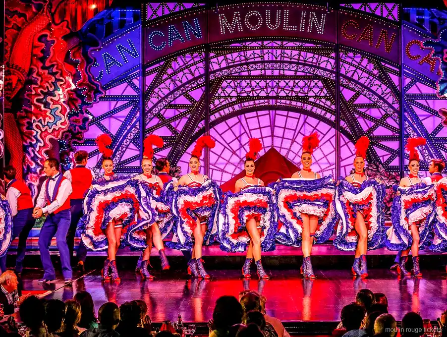Cancan-Tänzerinnen in Rüschenröcken vor dem Moulin Can Can Schriftzug auf der Bühne, Show mit Moulin Rouge Tickets