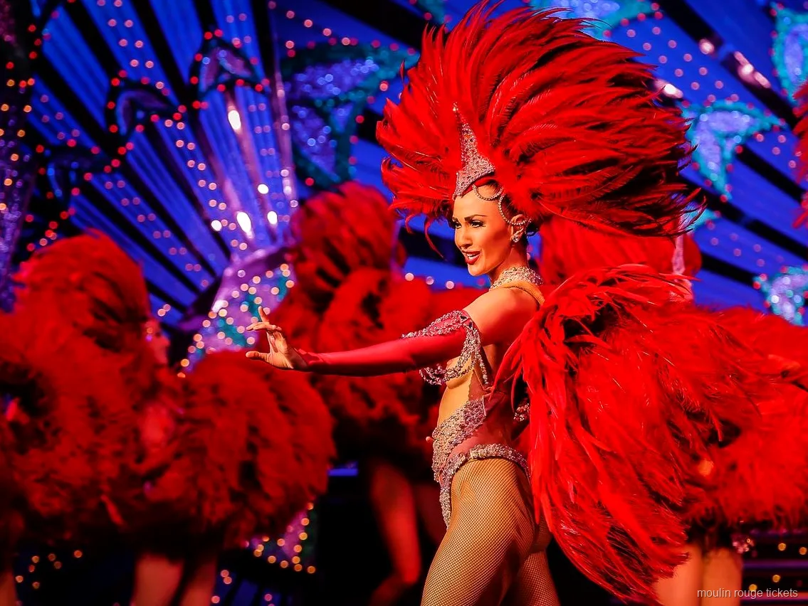 Ballarina amb un gran ventall de plomes vermelles davant d'un decorat blau il·luminat, entrades Moulin Rouge
