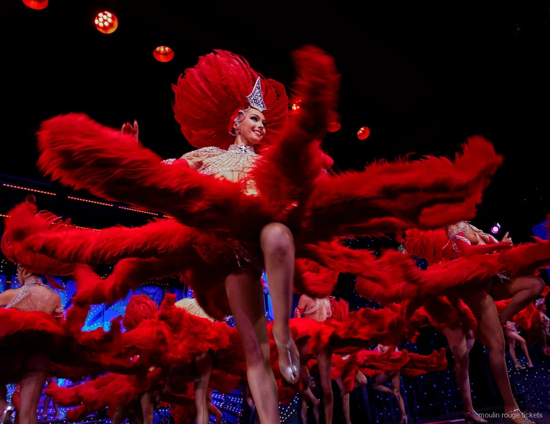 Dancers swirling huge red feather fans in a high kick, Moulin Rouge dinner show tickets with transport