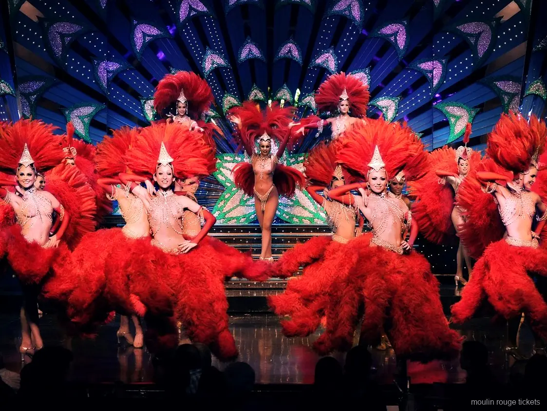 Dansere i røde fjerkostumer og glitrende hovedpynt på scenen, revyen du ser med Moulin Rouge billetter i Paris