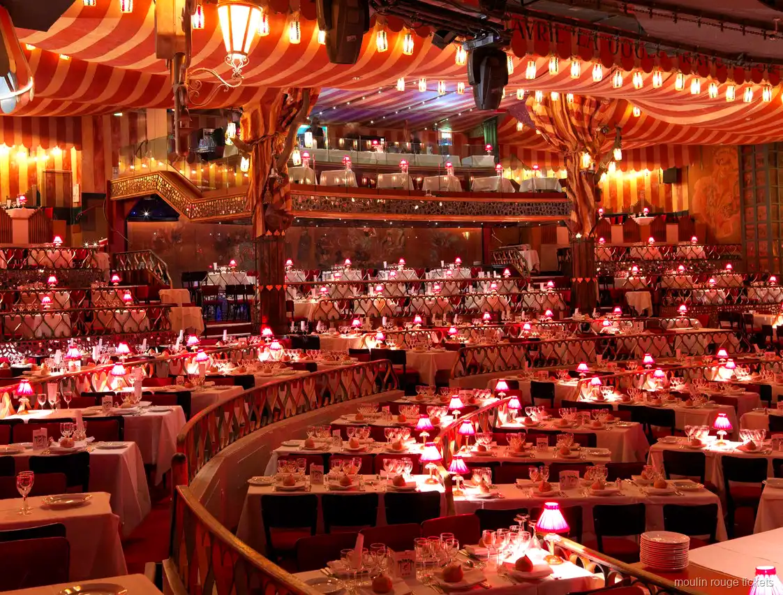 Moulin Rouge tickets: the cabaret hall with red striped ceiling, tiered tables and pink table lamps