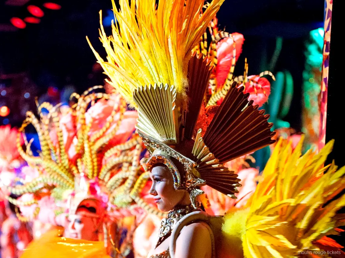 Moulin Rouge show tickets: dancer in a golden feather headdress with a fan crown on stage