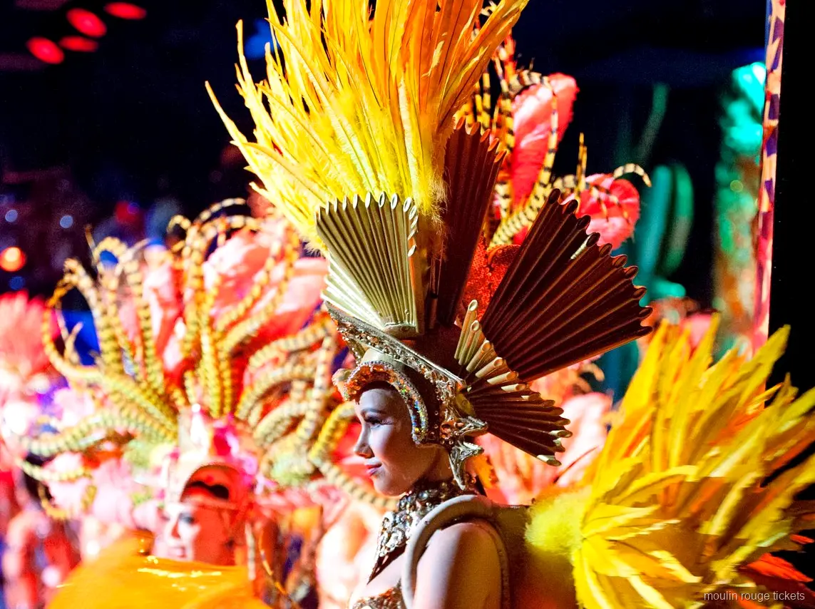 Moulin Rouge tickets: danseres met gouden verentooi en waaierkroon op het podium