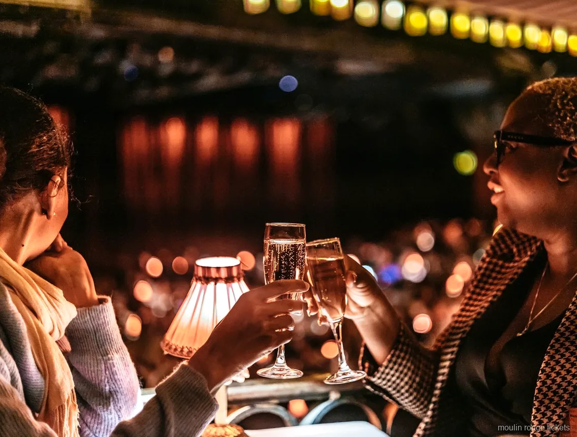 To gæster skåler i champagne ved et bord med lampe, Moulin Rouge billetter til aftenshowet