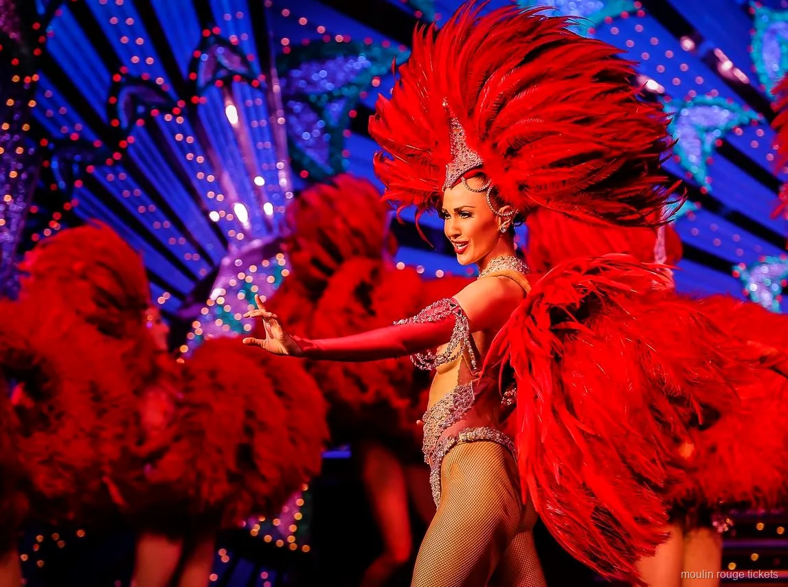 Tancerka z dużym wachlarzem z czerwonych piór przed niebieską scenografią, bilety Moulin Rouge