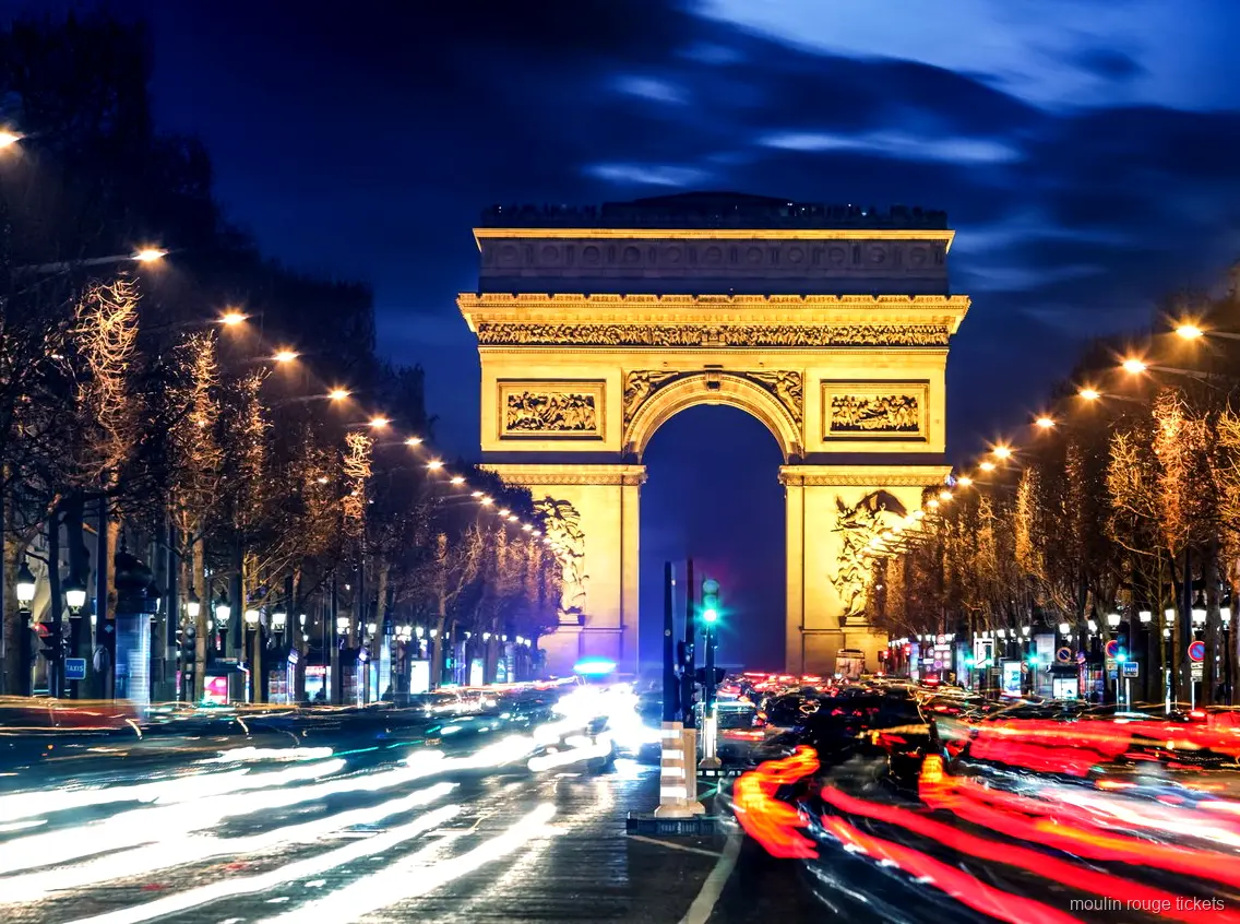 Arc de Triomphe illuminé la nuit au bout des Champs Élysées avec traînées lumineuses, avant les billets Moulin Rouge